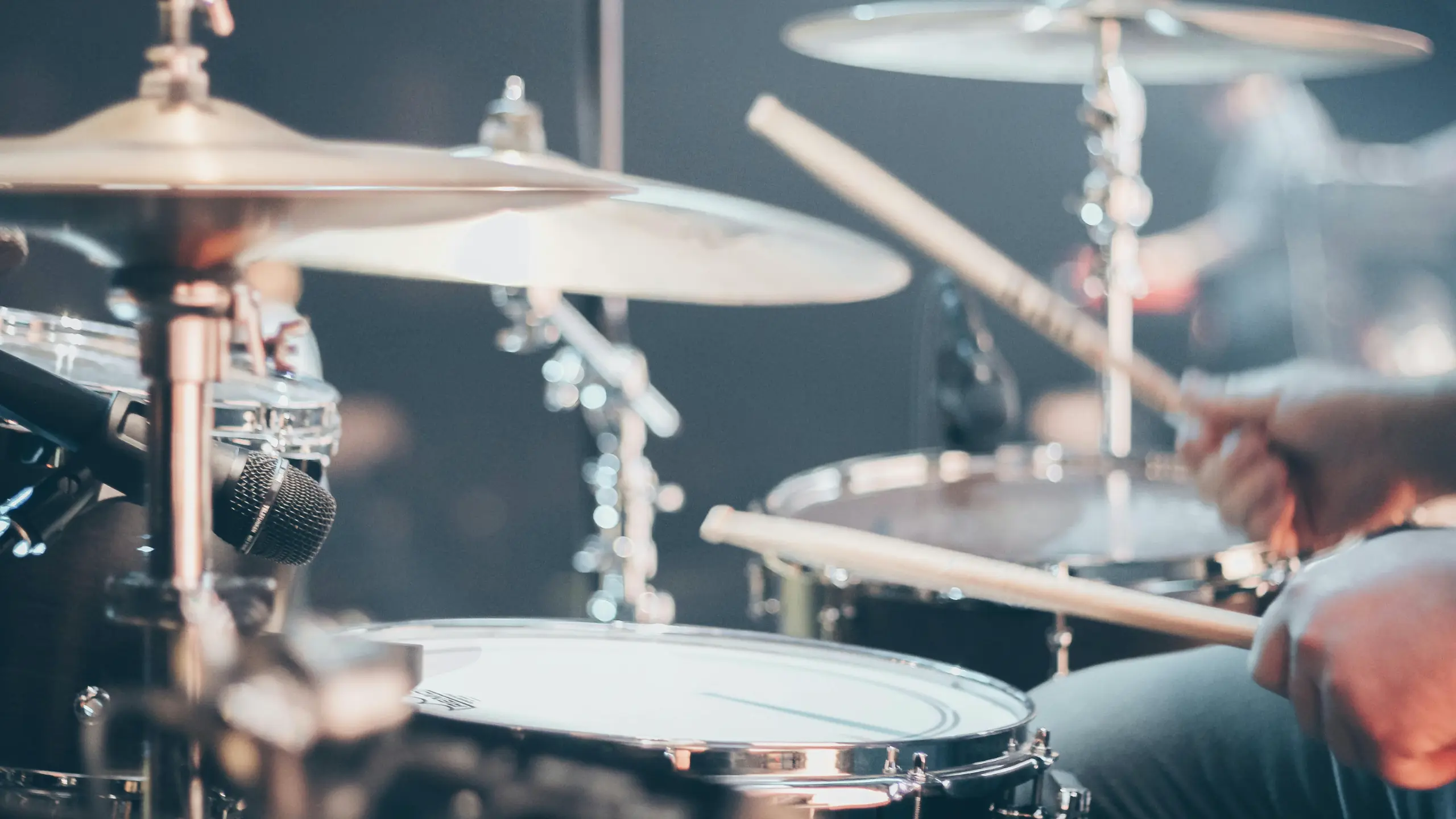 This is a stock photo of a person playing the drums. The drummers face is not shown. This picture was created by Josh Sorenson and was obtained from the Pexels website.